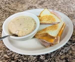 Ham and cheese sandwich with a cup of clam chowder.