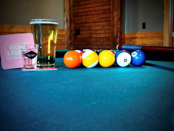 A pint of beer and a pool table setup with balls. 